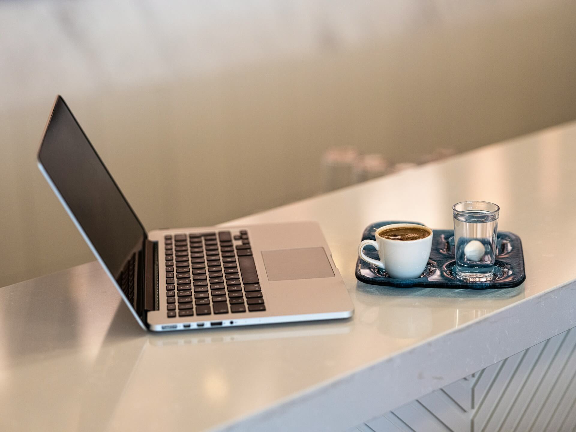 Ein Laptop mit der Website steht neben einem Gastronomie-Tablett mit Cafe